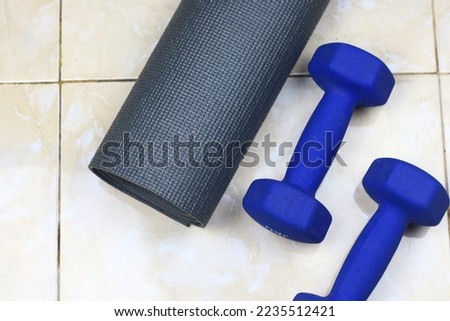 Grey Mattress, blue barbell and sport shoes on the floor. Indoor workout concept and healthy lifestyle. Sport equipment background.