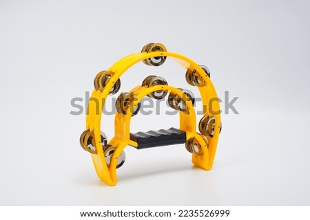 A tambourine with a plastic body and metal cymbals on a white background.
