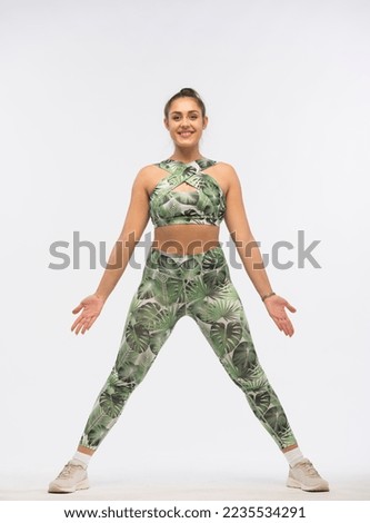 young woman doing fitness exercises on a white background.young bodypositive girl in a green tracksuit demonstrates fitness exercises for body shaping isolated.