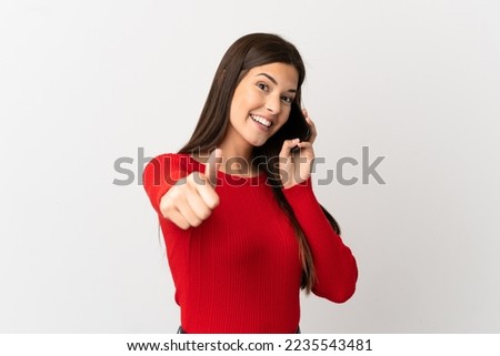 Teenager Brazilian girl using mobile phone over isolated white background with thumbs up because something good has happened Royalty-Free Stock Photo #2235543481