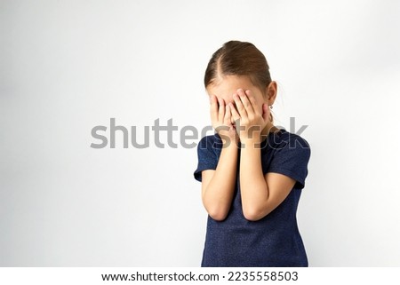 Little girl covering her eyes with her hands. Portrait of a girl cover her face, white background with copy space Royalty-Free Stock Photo #2235558503