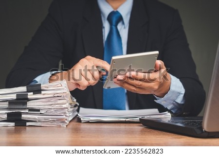 Tax day concept. A businessman in a suit uses a calculator to calculate taxes while sitting at the table in the office. Assistance with filing tax forms and calculation Royalty-Free Stock Photo #2235562823