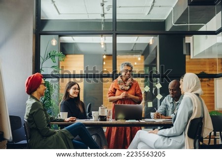 Successful businesspeople smiling happily during a meeting in a creative office. Group of cheerful business professionals working as a team in a multicultural workplace. Royalty-Free Stock Photo #2235563205