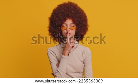 Shh be quiet please. Preteen child girl kid presses index finger to lips makes silence hush gesture sign do not tells gossip secret. Little funny children isolated alone on studio yellow background