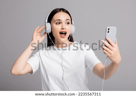 Surprised woman showing different emotions expressions wearing headphones and holding new cellphone and smartphone.