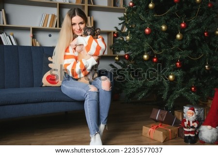 beautiful woman sits on a vintage couch with dog. on a background of a Christmas tree in a decorated room. happy new year.