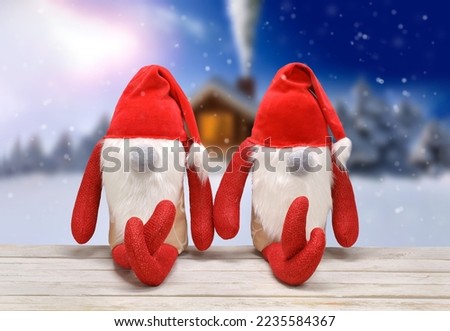 Two Christmas Elves are sitting on a bench, textile toys, winter landscape in the background and empty space for text
