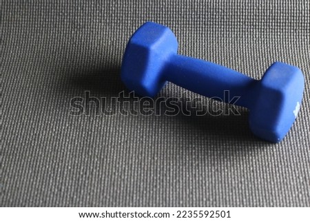 A blue barbell and grey sport mattress on the floor. Indoor workout concept and healthy lifestyle. Sport equipment background.