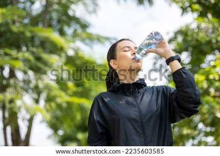 Happy slim woman drinking water after workout exercising in the city at sunrise. Young beautiful asian drinking water after jogging running outdoor. Healthy and active lifestyle concept. Royalty-Free Stock Photo #2235603585