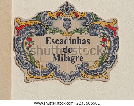 Beautiful street sign "Miracle Stairs" or "Escadinhas do Milagre" in Portugal. Fragment of traditional Portuguese concrete signs with road name of colorful ceramic tiles Azulejo.