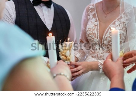 The bride and groom hold a traditional burning candle in the family hearth. Traditions of wedding celebration.
