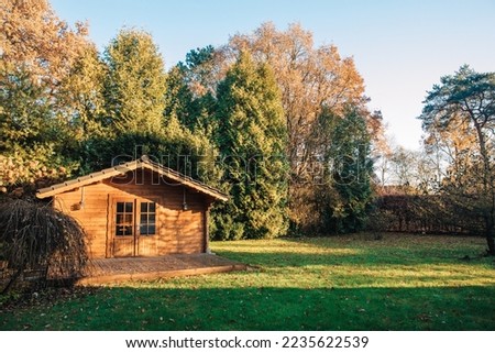Small wooden house in a beautiful garden with lots of sun. Garden in summer or spring. Wooden garden shed. Secluded little cottage in the woods Royalty-Free Stock Photo #2235622539