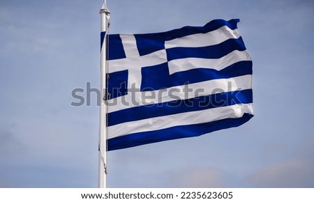 Wide angle view from the bottom of the pole to the top with the Greece flag winding against cloudy sky.