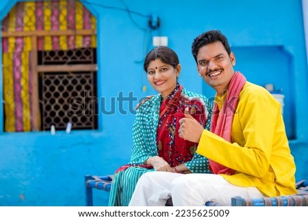 Happy Indian farmer with wife showing thumps up at home.