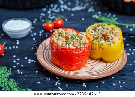 Stuffed pepper. Stewed pepper
 with rice and minced meat. Baked peppers in a cast iron pan on a black background. Healthy Romanian food.