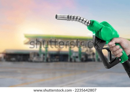 Holding a fuel nozzle against with gas station blurred background Royalty-Free Stock Photo #2235642807