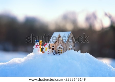 two cute snowmans and little house on snow. winter nature background.  Christmas and New Year holidays concept. festive winter season