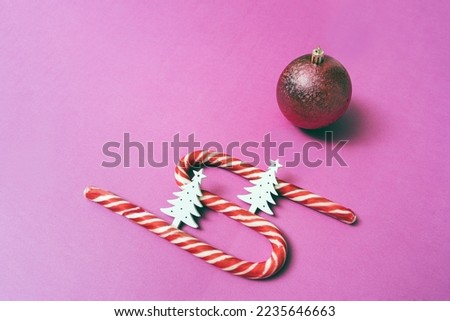Minimalistic christmas pattern, new year holiday candy canes with white fir trees and one toy on uniform background, abstract flat lay for background, top side view. Copy space