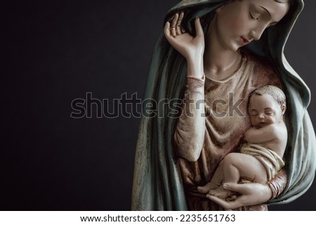 Virgin Mary and infant Jesus in her arms on a black background with copy space  Royalty-Free Stock Photo #2235651763