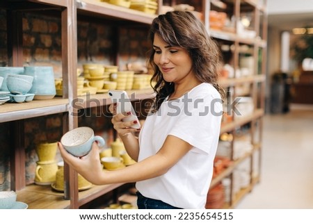 Happy female ceramist taking a picture of an earthenware product. Cheerful businesswoman creating content to advertise on her online store. Creative young woman running a successful small business.