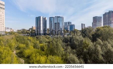 Multi-storey building made of glass and plastic. New residential complex next to the park. Cityscape overlooking the park. Park green areas in a big city. Photos of Novosibirsk, Russia