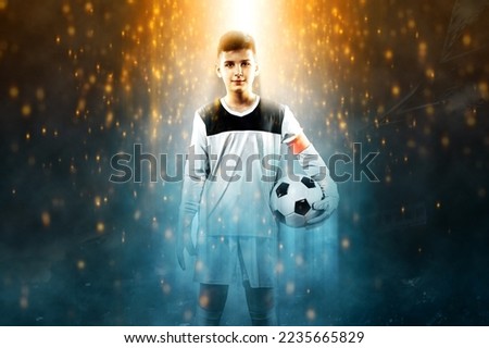 Football player. Kid - soccer champion. Boy goalkeeper in sportswear on stadium with ball. Sport concept.