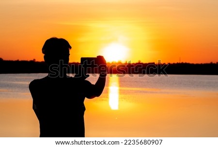 Silhouette, Man using smartphone take photo sunset at lake
