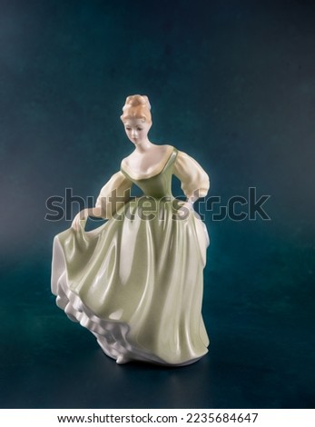 Bone China Woman figurine isolated on a dark green  background Royalty-Free Stock Photo #2235684647