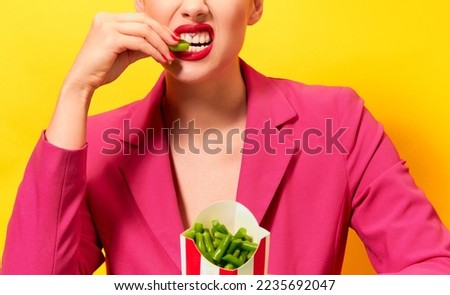 Cropped image of young woman in bright pink jacket eating green beans over yellow background. Dieting. Food pop art photography. Health care. Complementary colors. Copy space for ad, text