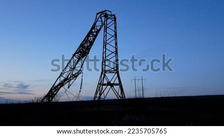 A broken power pole in the middle of the field. Russia attacks Ukraine's energy system Royalty-Free Stock Photo #2235705765