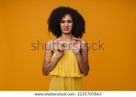Young woman in yellow dress expressing disgusting isolated over yellow wall