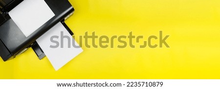 Top view of a black printer and a blank sheet of a4 paper on a yellow background, layout.Office Equipment, close-up.Copy space. Banner.Photo printing on a photo printer