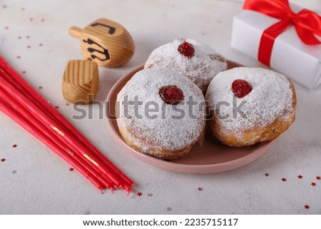 Plate with tasty donuts, dreidels, candles and gift for Hannukah celebration on white background