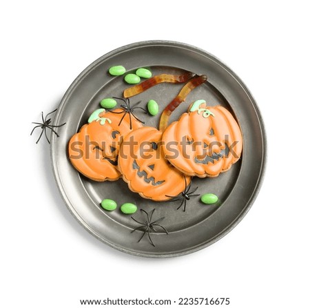 Plate with Halloween pumpkin cookies, jellies and spiders on white background