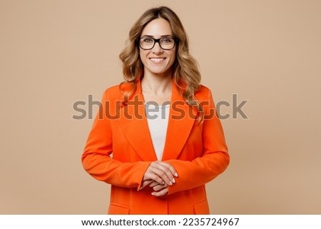 Young fun smiling happy successful employee business woman corporate lawyer 30s wearing classic formal orange suit glasses work in office look camera isolated on plain beige color background studio Royalty-Free Stock Photo #2235724967