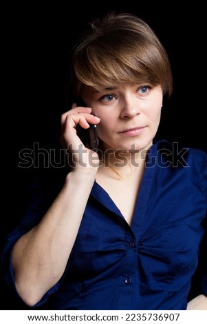Young businesswoman talks over her mobile phone, isolated on black background 