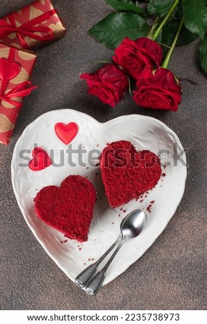 Cakes Red velvet in the shape of hearts on white plate, roses and wine for Valentines Day on brown background, Top view