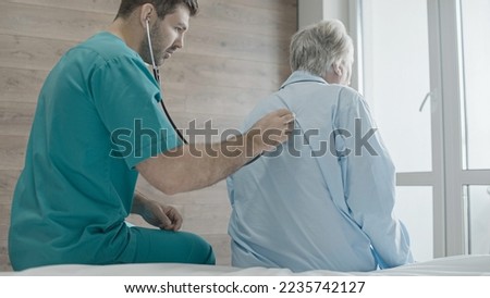 Male practitioner listening to patient's lungs using stethoscope, pneumonia