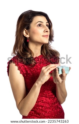 Beautiful young woman thinking at the content of her gift holding a small blue box  in the hands 