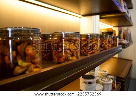 Spicy dry fruit cashew nuts packed in glass bottle arranged in racks in shop