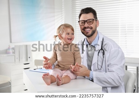 Pediatrician examining cute little baby in clinic Royalty-Free Stock Photo #2235757327