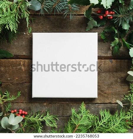 Christmas frame. Mockup poster. Blank square canvas on wooden background with Christmas greenery.
