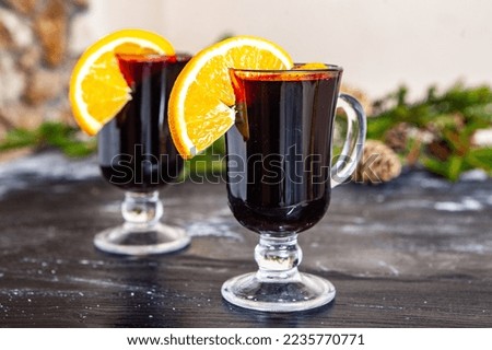 Glass of delicious glintwein or mulled hot wine, cinnamon, thread on vintage wooden background.