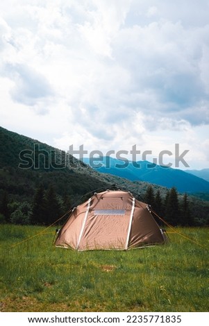 A brown tourist tent, with a quick-set system, stands on top of a mountain. A wonderful warm summer morning, the concept of freedom and travel. Vertical photo