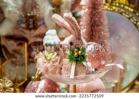 Christmas decor in pastel pink colors. On a decorated festive table in a vase there is a pink rabbit, and pink balls close-up. chrysalis