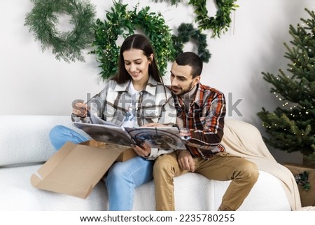 Photo shoot in the studio of a young couple. A guy with a girl is celebrating Christmas. New Year's love story. A couple looks at their wedding photos.