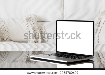 Laptop with white screen. Isolated laptop screen. Laptop view from right angle. Laptop on a black glass table against a white sofa.