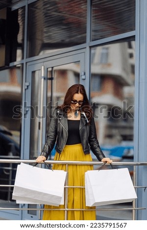 Portrait of young pretty stylish girl holding the shopping bags and looking forward in a good mood. Ideal shopping.