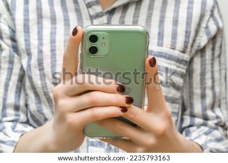 Female young hands using mint green smart phone.business woman holding mobile phone checking social media,news,playing mobile games,texting messages closeup. Gadget blogging. Mobile apps advertising