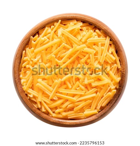 Shredded cheddar cheese, in a wooden bowl. Grated natural cheese, piquant, colored orange with annatto, a natural food coloring. Rolled in starch to avoid sticking. Used for pizza and pasta dishes. Royalty-Free Stock Photo #2235796153